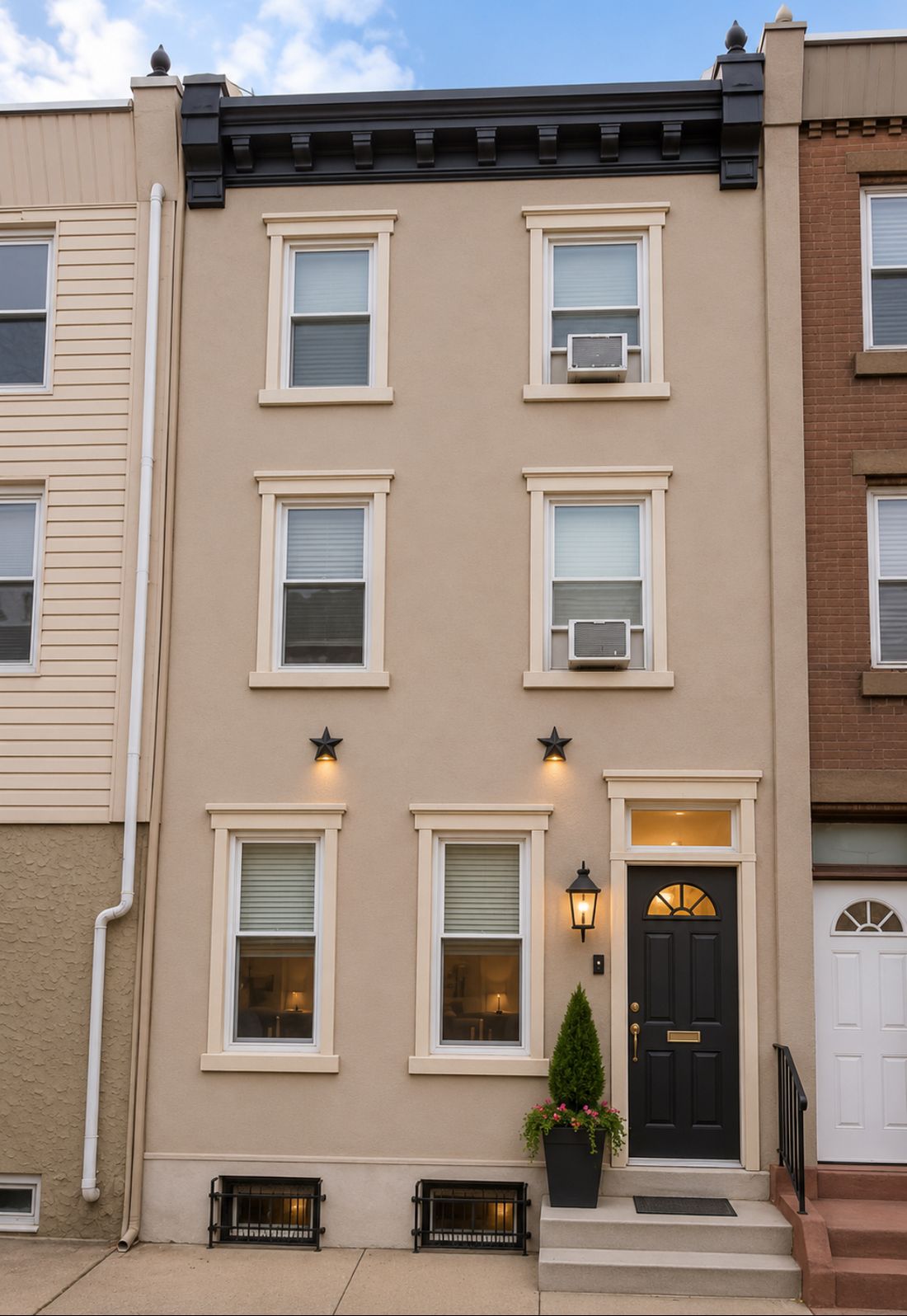 Rowhome exterior after: refinished stucco facade with black cornice and lighting